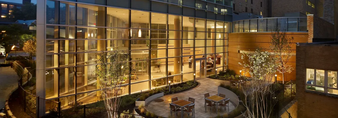 Exterior of St. Joseph's University Medical Center at night, with view of a bright lobby area through its windows.