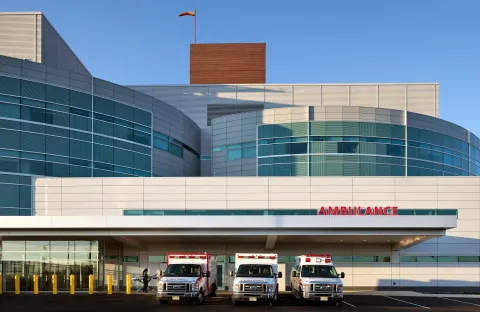 Exterior of St. Joseph's University Medical Center, with three ambulances parked beneath an "Ambulance" sign.
